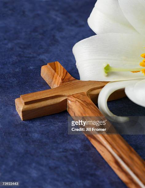 a wooden cross and an easter lily on a blue background - easter lilies and cross stock pictures, royalty-free photos & images
