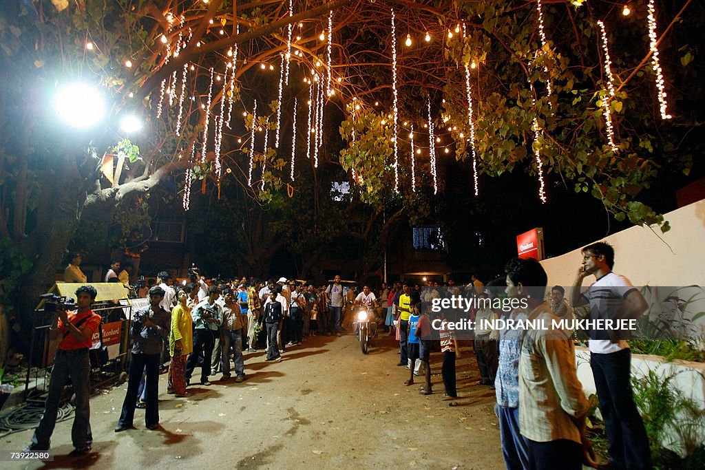 Curious onlookers and cameramen stand at...