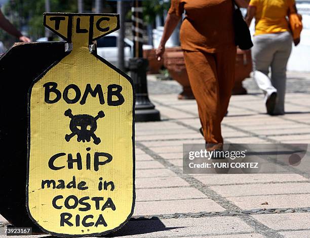 Peatones caminan junto a un cartel con una leyenda en ingles contra de un Tratado de Libre Comercio con Estados Unidos, frente a la sede de la...