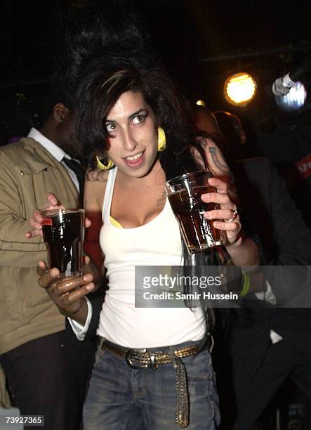 Amy Winehouse carries two drinks as she arrives on stage to perform live at the Dublin Castle as part of The Camden Crawl on April 19, 2007 in...