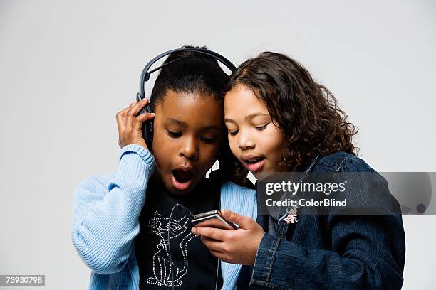 two young girls (8-9) looking at mp3 player - blind white background stock pictures, royalty-free photos & images