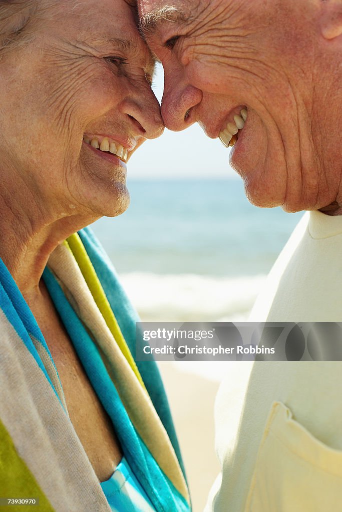 Senior couple smiling face to face on beach, close up