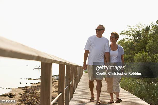 couple walking along boardwalk by sea - boardwalk stock pictures, royalty-free photos & images