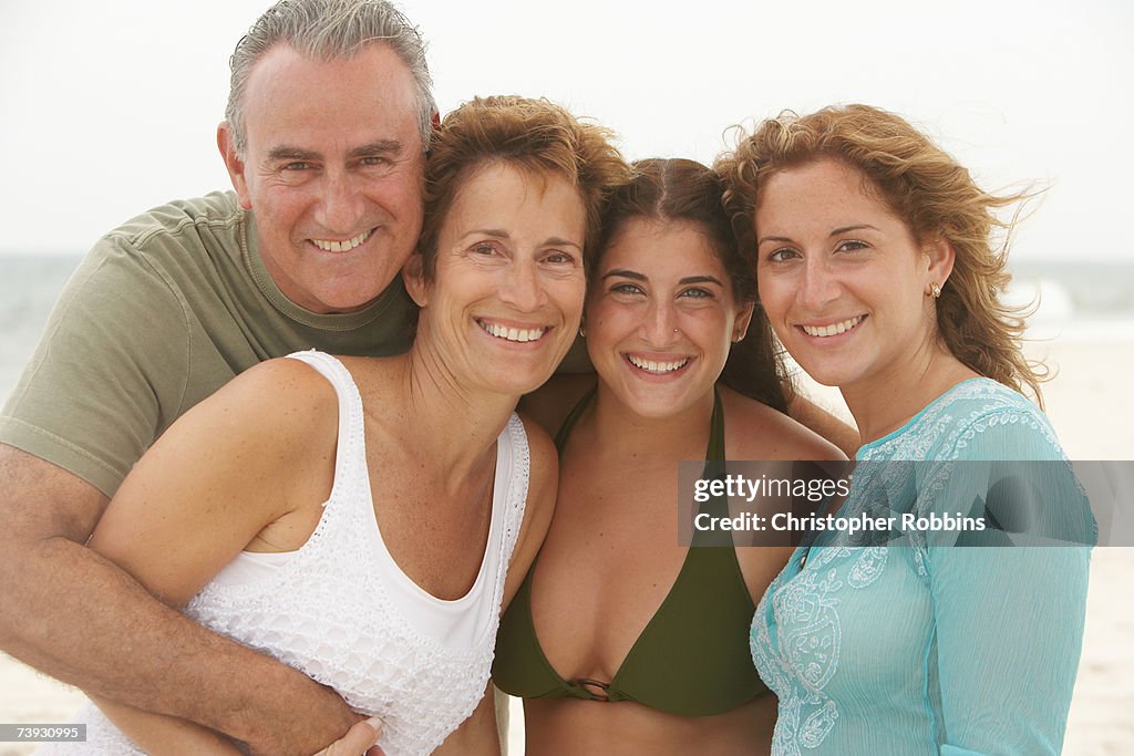 Family smiling on beach, waist up
