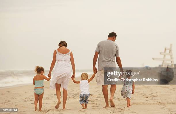 family with children (4-7) walking on sandy beach, rear view - family with three children fotografías e imágenes de stock