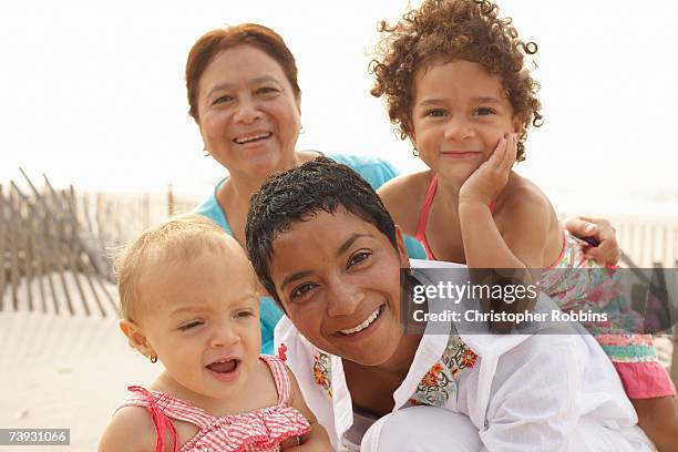 family with children (15 months - 4 years) crouching down on sandy beach - woman 30 years old portrait stock pictures, royalty-free photos & images
