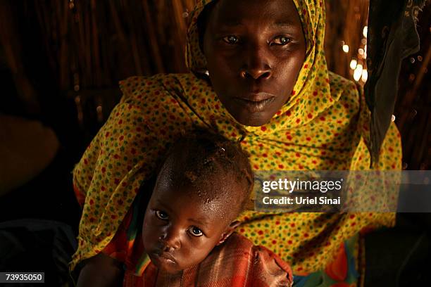 Blind Sudanese refugee Fathna Ibrahim, who lost her husband and was tortured by members of Janjaweed, sits with her daughter in a hut in the Goz Amir...