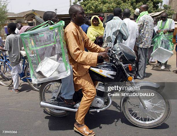 Nigerian INEC official carries a box on his bike 21 April 2007 after dispatching voting material during the first round of presidential election in...