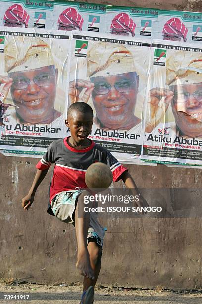 Child plays with a ball backdropped by posters of presidential candidate Atiku Abubacar 21 April 2007 in Lagos on the first day of polling to choose...
