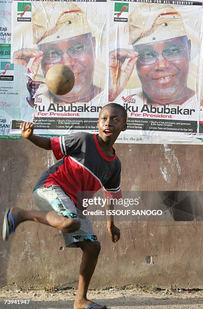 Child plays with a ball backdropped by posters of presidential candidate Atiku Abubacar 21 April 2007 in Lagos on the first day of polling to choose...