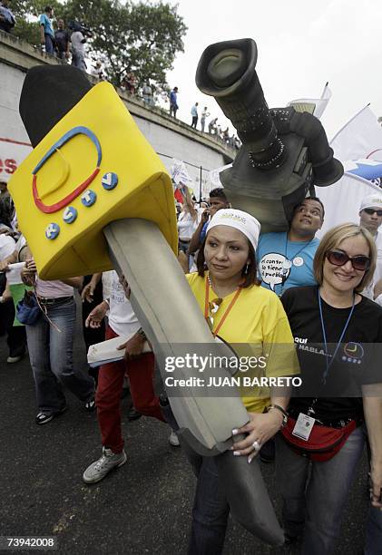 Radio Caracas Television private television journalists carry mockups of a microphone and a TV camera during a demonstration in support of the...