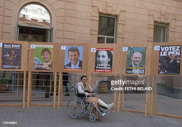 French citizen poses on a wheelchair in front of electoral billboards at the entrance of the French consulate in Tunis, 22 April 2007. Voting started...