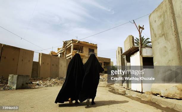 Two Iraqi women walk near a blast wall on April 22, 2007 in the Karrada neighborhood of Baghdad, Iraq. U.S troops are building a wall, that the...