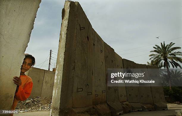 An Iraqi girl stands near a blast wall on April 22, 2007 in the Karrada neighborhood of Baghdad, Iraq. U.S troops are building a wall, that the...