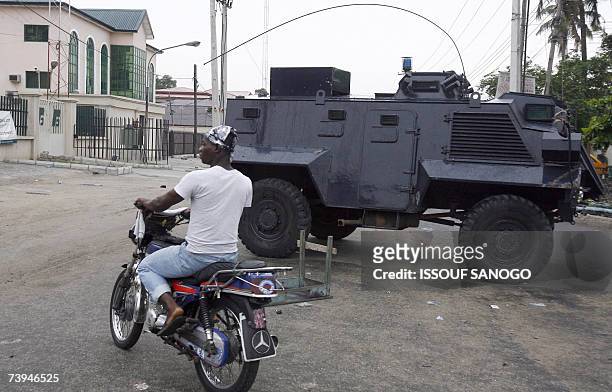 Motorcyclist rides past a Nigerian tank deployed at the Independent Electoral Commission headquarters 22 April 2007 in Lagos on the eve of the...
