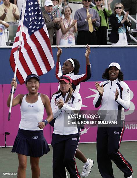 Delray Beach, UNITED STATES: Vania King carries the US national flag as teammates Lisa Raymond, Venus, and Serena Williams celebrate their victory...