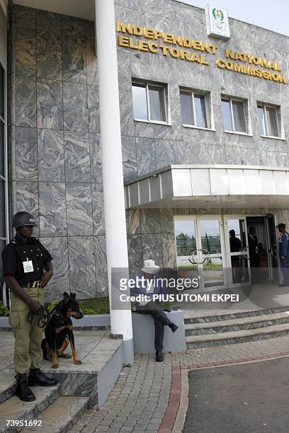 Policeman holds a guard dog at the entrance of INEC headquaters where Professor Maurice Iwu annouced the results of the presidential election, in...