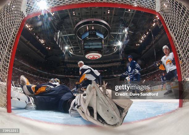 The puck bounces on the back of goaltender Ryan Miller of the Buffalo Sabres as Kyle Wellwood of the Toronto Maple Leafs and Brian Campbell of the...