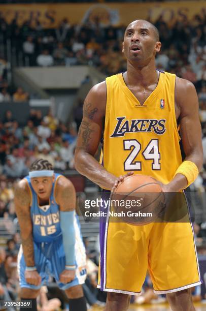 Kobe Bryant of the Los Angeles Lakers shoots a free throw while Carmelo Anthony of the Denver Nuggets stands in the background at Staples Center on...