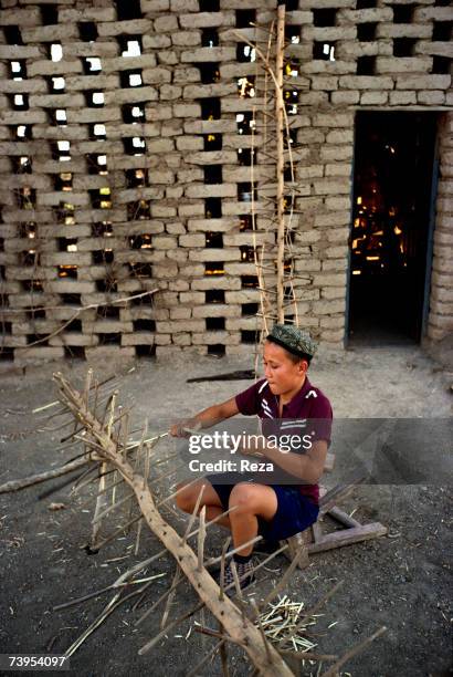 An Uighur boy makes a wooden rack outside a drying shed in Turpan August, 1995 in Turpan, China.
