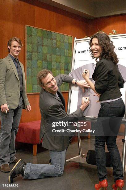 Actors Jesse Spencer, Hugh Laurie, and Lisa Edelstein pose the announcement of the creation of exclusive ''House-ism'' t-shirts to benefit the...