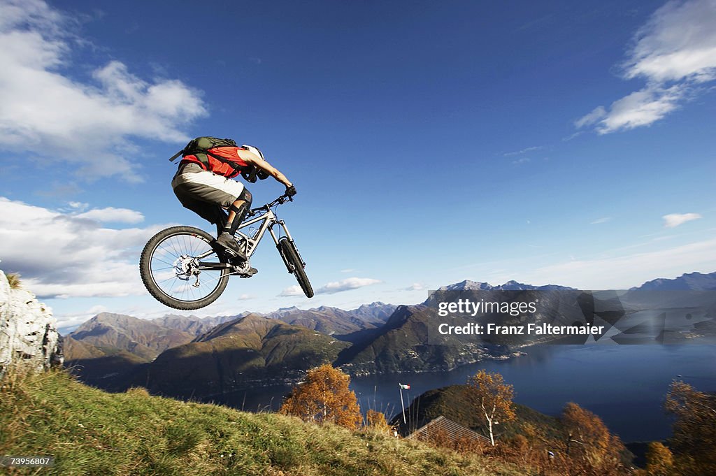 Italy, Lake Como, man performing jump on bicycle