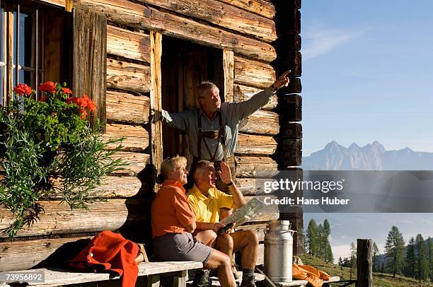 mature couple sitting in front of alpine hut, talking to farmer - alpine lodge stock-fotos und bilder