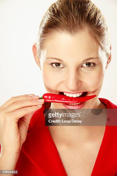 young woman holding chilies between teeth, close-up, portrait - female eating chili bildbanksfoton och bilder