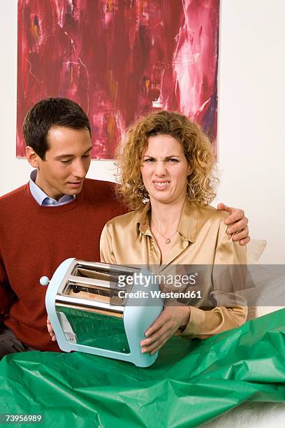couple sitting on sofa, woman holding toaster - bad gift stock pictures, royalty-free photos & images