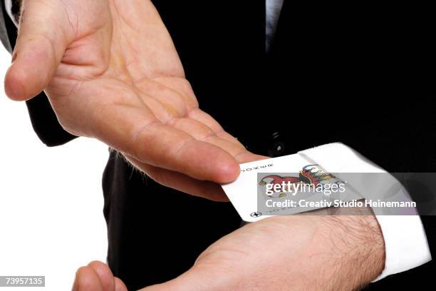 man extracting playing card out of sleeve, close-up, mid section - joker card stock pictures, royalty-free photos & images