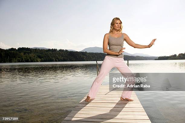 woman exercising yoga on jetty - taijiquan foto e immagini stock