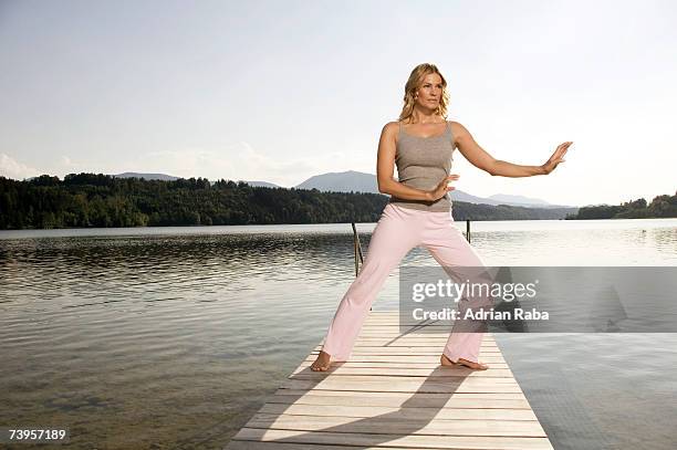 woman exercising yoga on jetty - tai chi shadow stock pictures, royalty-free photos & images