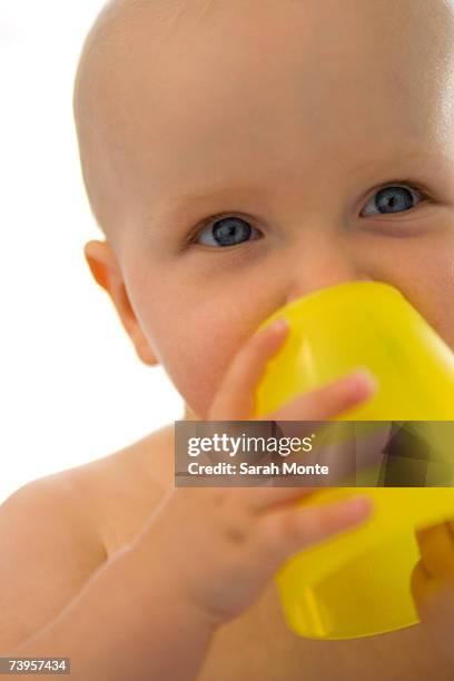 baby boy (6-12 months) holding yellow cup, close-up - first exposure series stock pictures, royalty-free photos & images