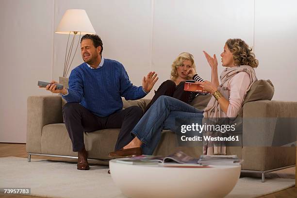 parents with daughter sitting on sofa in living room - argue stock pictures, royalty-free photos & images