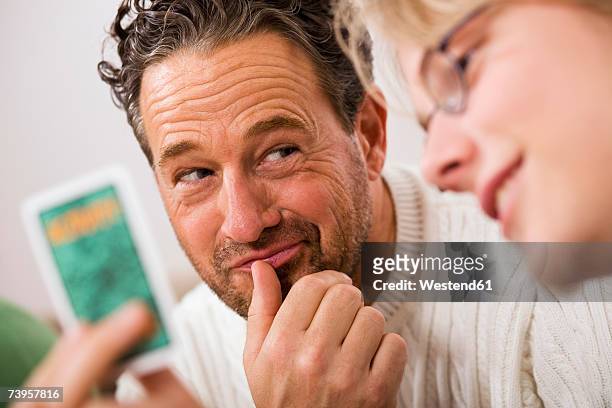 son (16-17) showing father playing card (focus on background) - card game mature people stock-fotos und bilder