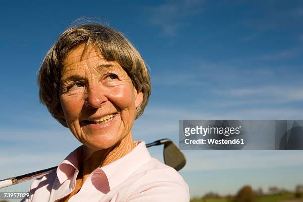 senior adult woman holding golf club - golf short iron stock pictures, royalty-free photos & images