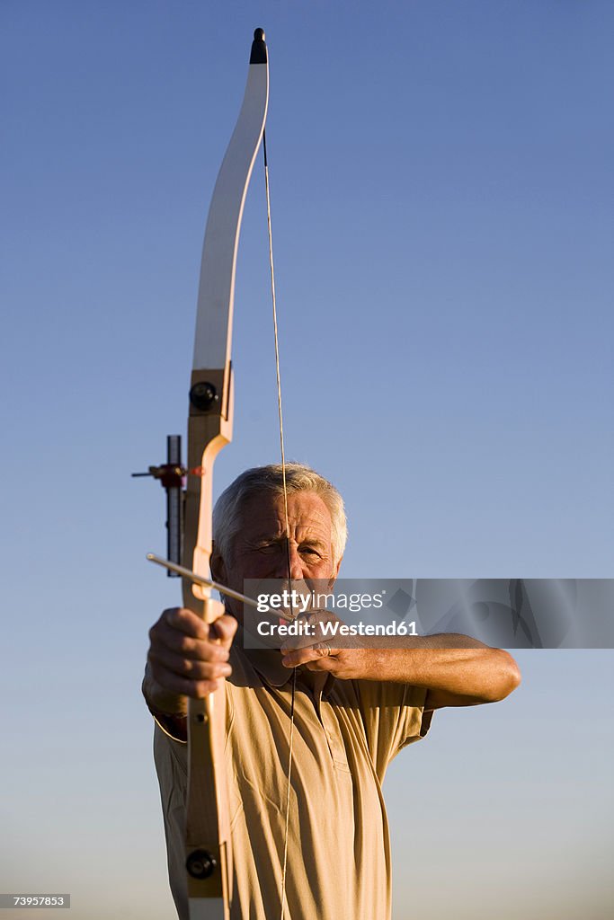 Senior adult man using bow and arrow