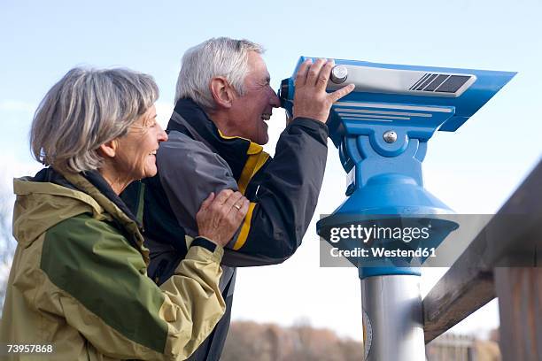 senior couple, man looking through telescope, side view - looking through an object stock pictures, royalty-free photos & images