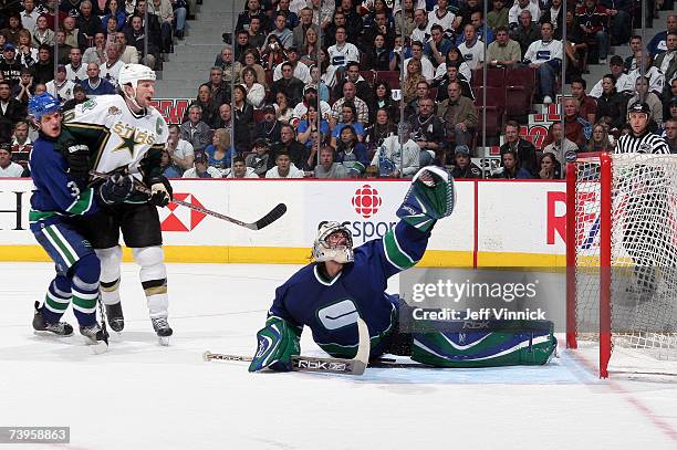 Roberto Luongo and Kevin Bieksa of the Vancouver Canucks and Brendan Morrow of the Dallas Stars watch as the shot of Mike Modano of the Stars hit the...
