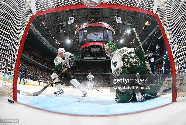 Jon Klemm of the Dallas Stars tries to pry the puck out of the net behind teammate Marty Turco as Daniel Sedin of the Vancouver Canucks celebrates...