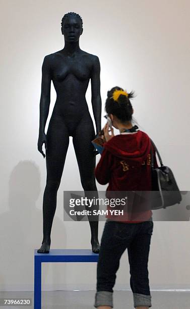 Woman admires Italian artist Giuseppe Bergomi's bronze statue "Modella nera su tavolino Ikea" on display in the Tapei Fine Arts Museum 25 April 2007....