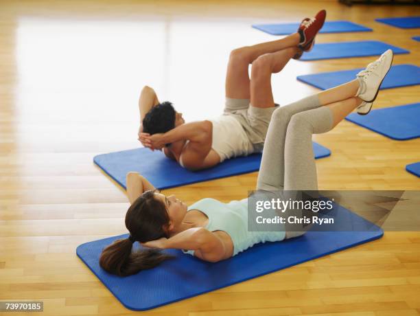 couple doing mat exercises in a fitness studio - vloerturnen stockfoto's en -beelden