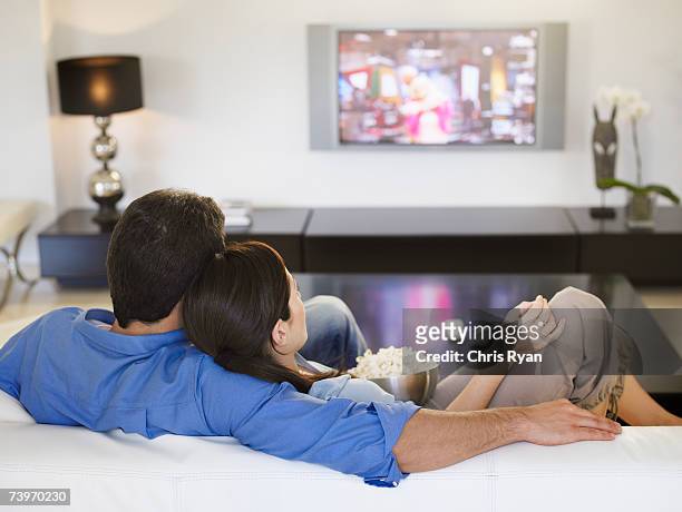 pareja juntos viendo la televisión y comiendo palomitas de maíz - familia viendo tv fotografías e imágenes de stock