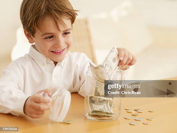 boy putting money into a cookie jar - child cookie jar stock pictures, royalty-free photos & images