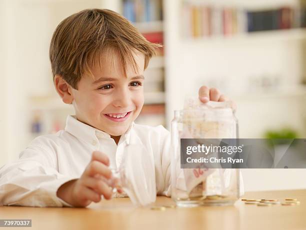 boy putting money into a cookie jar - kids making money stock pictures, royalty-free photos & images