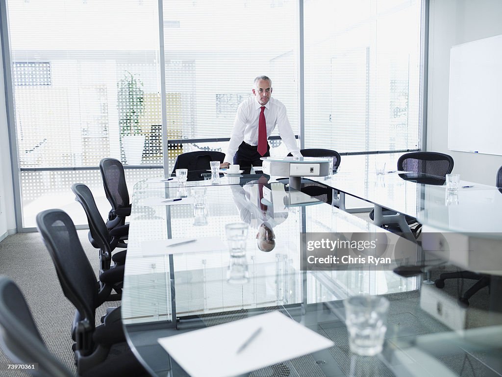 Businessman alone in a boardroom leaning on table
