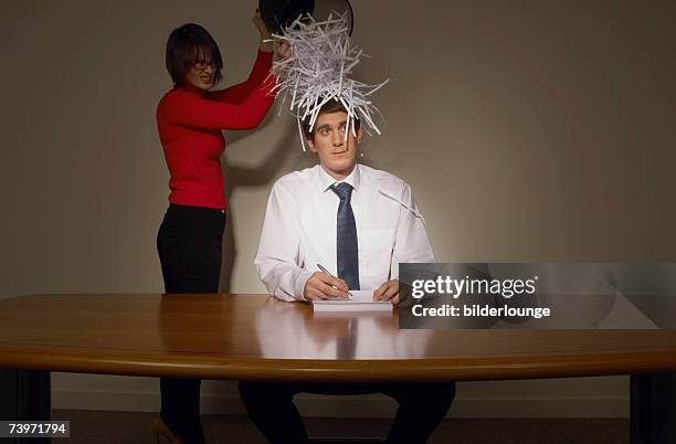 businesswoman emptying wastebasket over her colleague - business revenge stock pictures, royalty-free photos & images