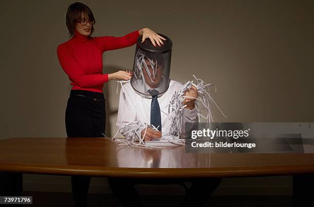 businesswoman emptying wastebasket over her colleague - business revenge stock pictures, royalty-free photos & images