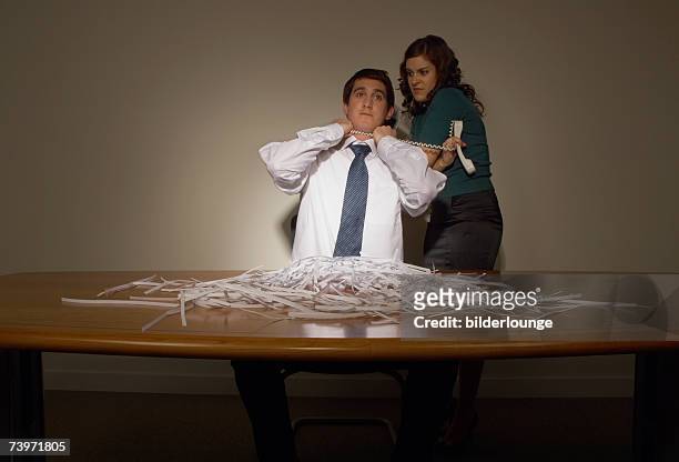 businessman sitting at untidy desk strangled by female colleague with telephone cord - business revenge stock pictures, royalty-free photos & images