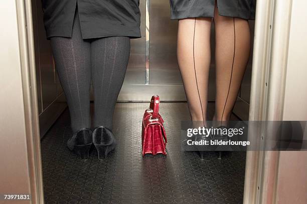 rear view of two women's legs standing in elevator together - seamed stockings stock pictures, royalty-free photos & images